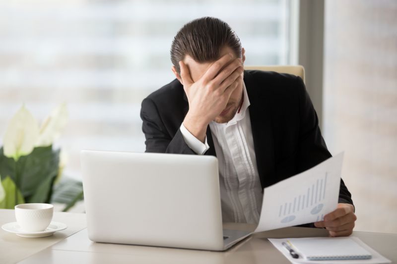 A man with his hand on his face looking at a chart.