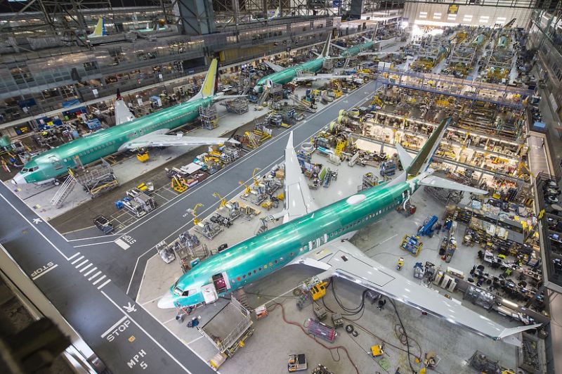 Three aircraft in a large hangar, with people and displays surrounding them.