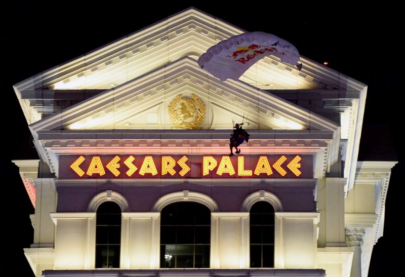 Caesars Palace sign with a skydiver coming down in front of it at night