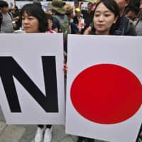 South Korean protesters hold placards that play on the Hinomaru during a rally in Seoul on July 20.