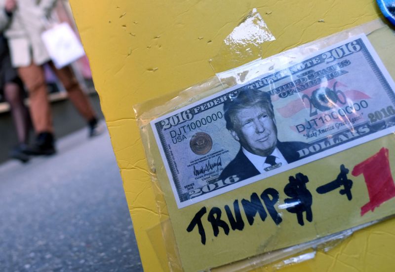 A fake dollar bill with US Republican presidential candidate Donald Trump's picture on it is displayed for sale with other electoral items at a roadside stall as pedestrians walk past in New York on February 26, 2016. White House hopefuls Ted Cruz and Marco Rubio unleashed a barrage of attacks against Donald Trump during raucous Republican debate on February 25, as they sought to halt the billionaire frontrunner's seemingly relentless march to the party's nomination. / AFP / Jewel Samad (Photo credit should read JEWEL SAMAD/AFP/Getty Images)