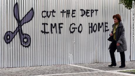 A woman walks past a slogan in central Athens in 2015 protesting the IMF bailout program that led to years of tough austerity measures.