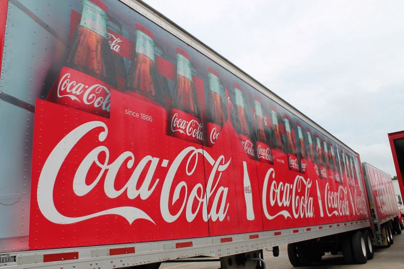 Side of semi trailer truck with Coca-Cola bottles on it.