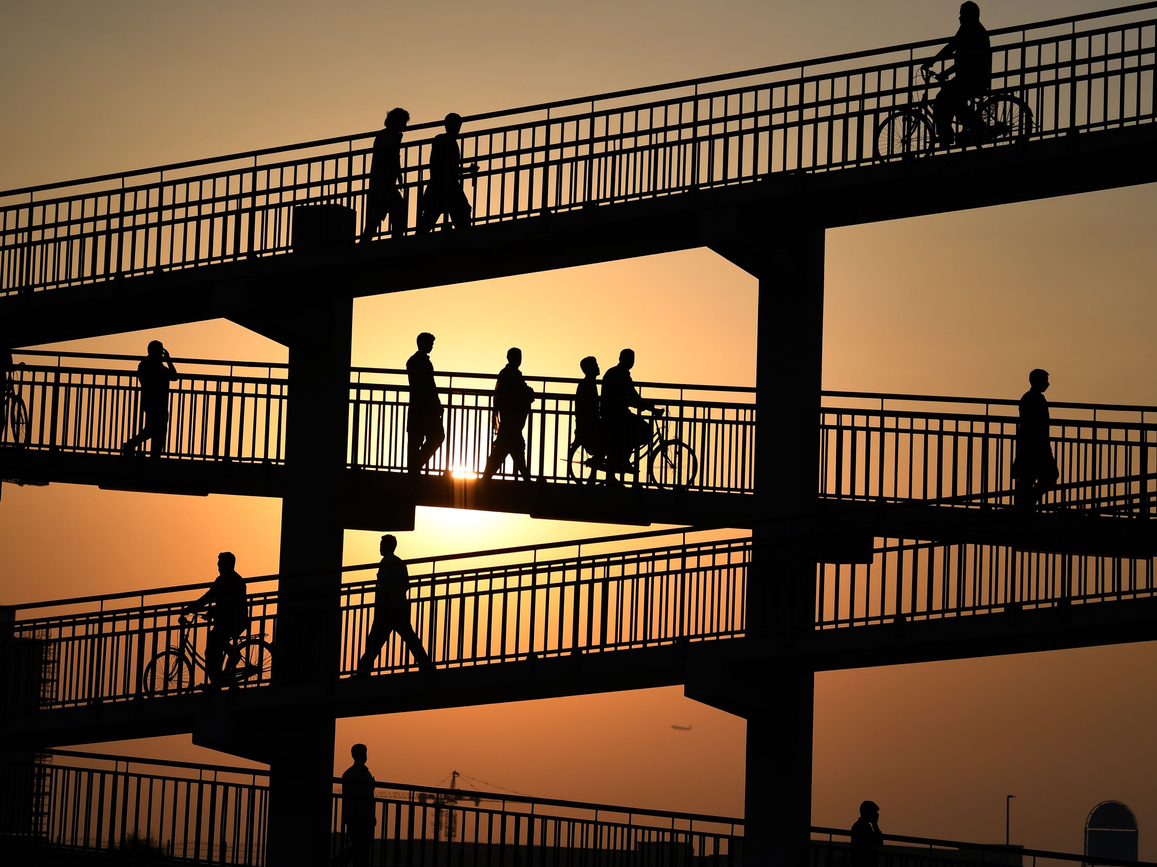 Asian labourers cross a pedestrian bridge in Dubai on August 7, 2019, as they head to work at a vegetable market.