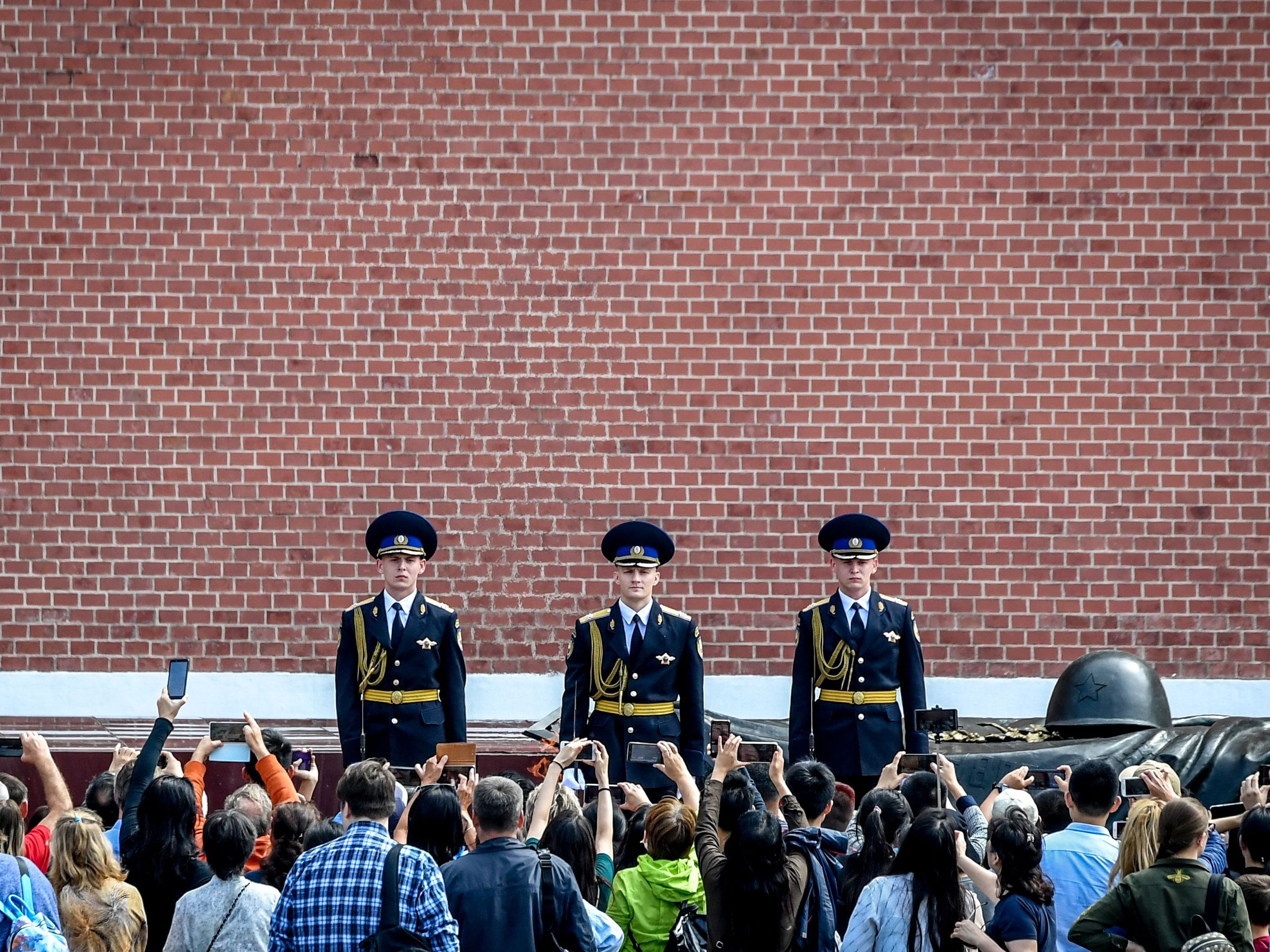 People take pictures of Russian honour guards during the changing of the guards ceremony at the Tomb of the Unknown Soldier by the Kremlin wall in Moscow on August 7, 2019.