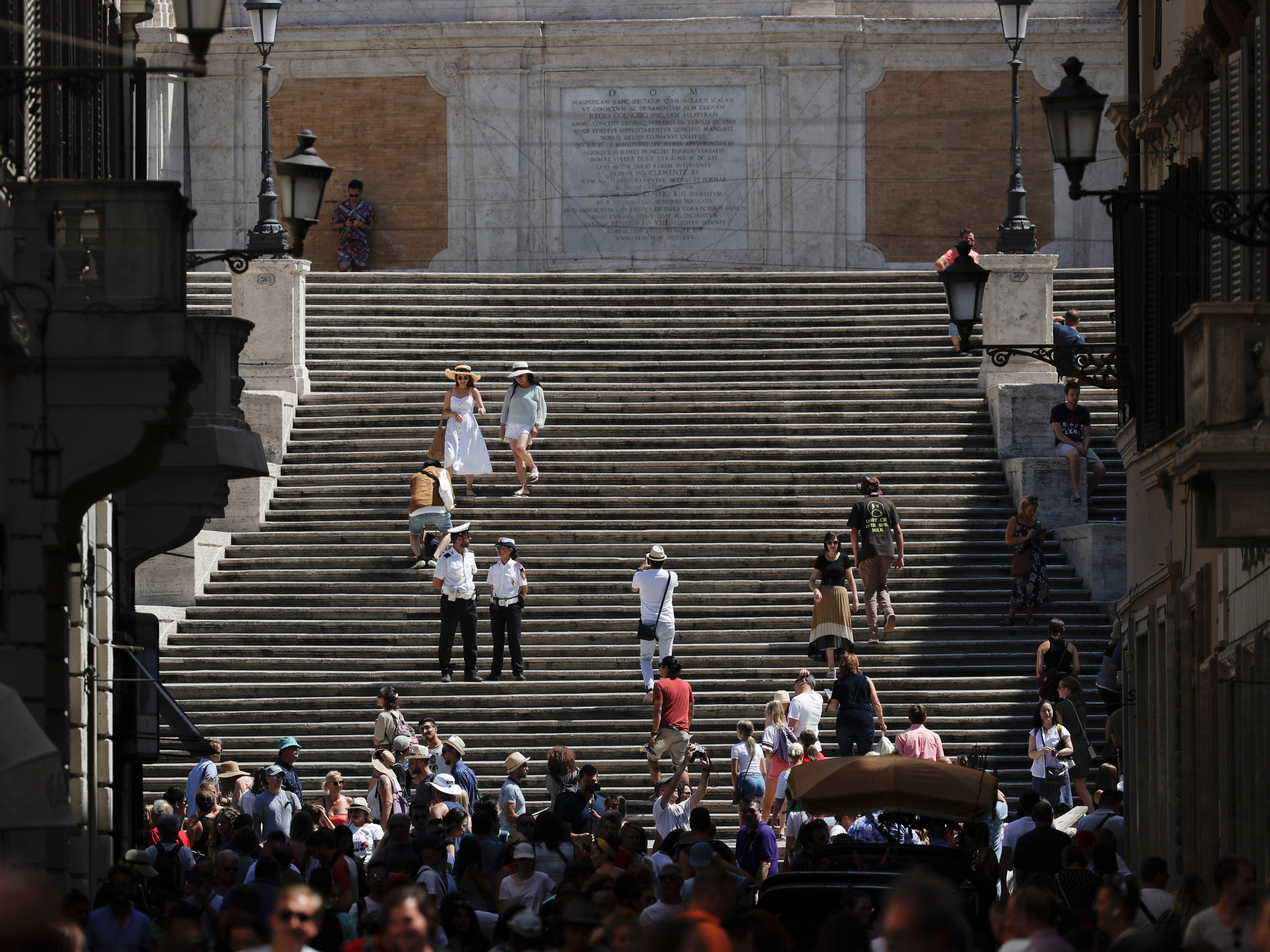 People walk down the Spanish Steps, in Rome on Aug. 7, 2019. Police started the enforcement of a law designed to protect monuments and landmarks and are forbidding people from sitting on the Spanish steps since they are considered a monument.