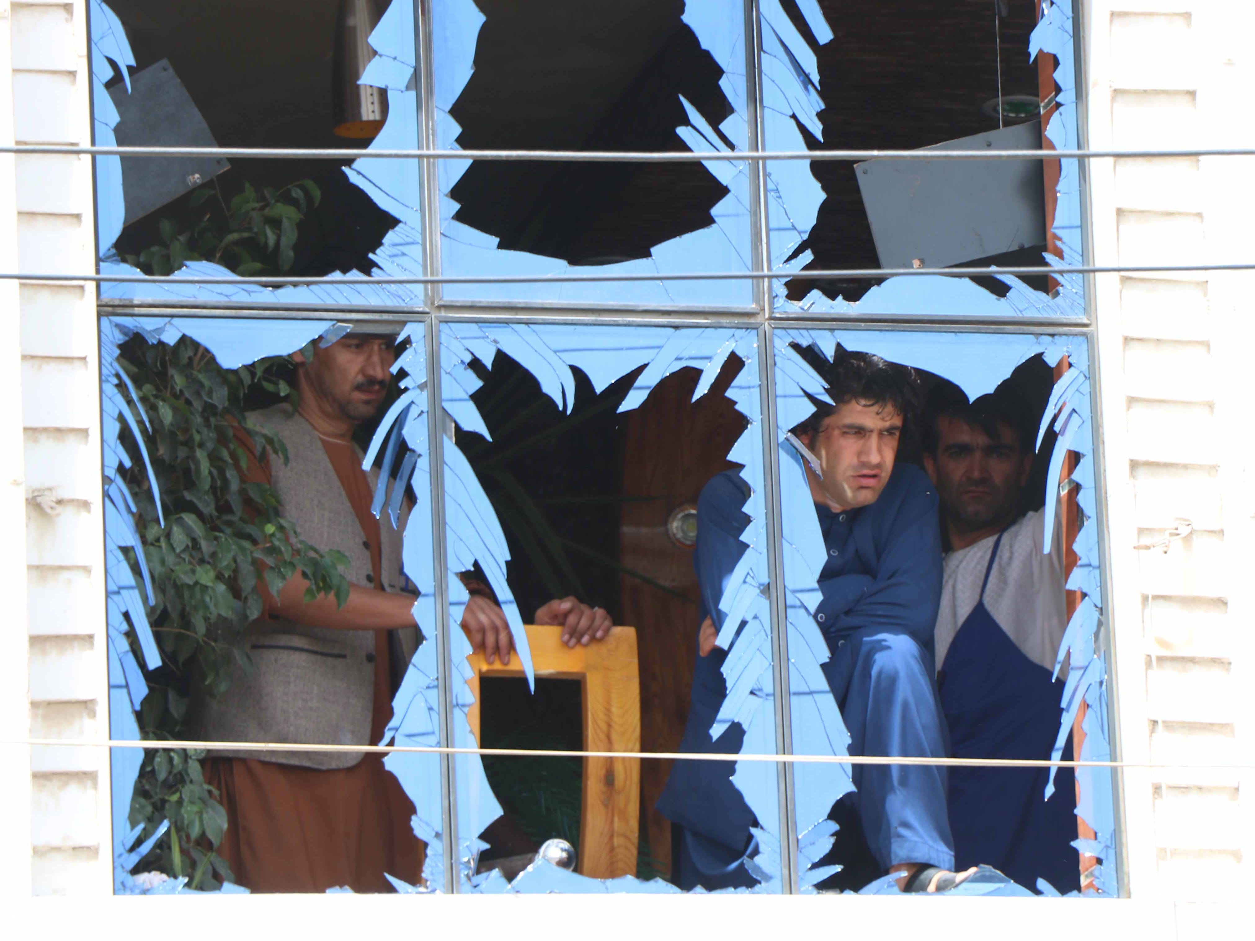 People peer through damaged window panes near the scene of a bomb blast in Herat, Afghanistan on August 7, 2019.