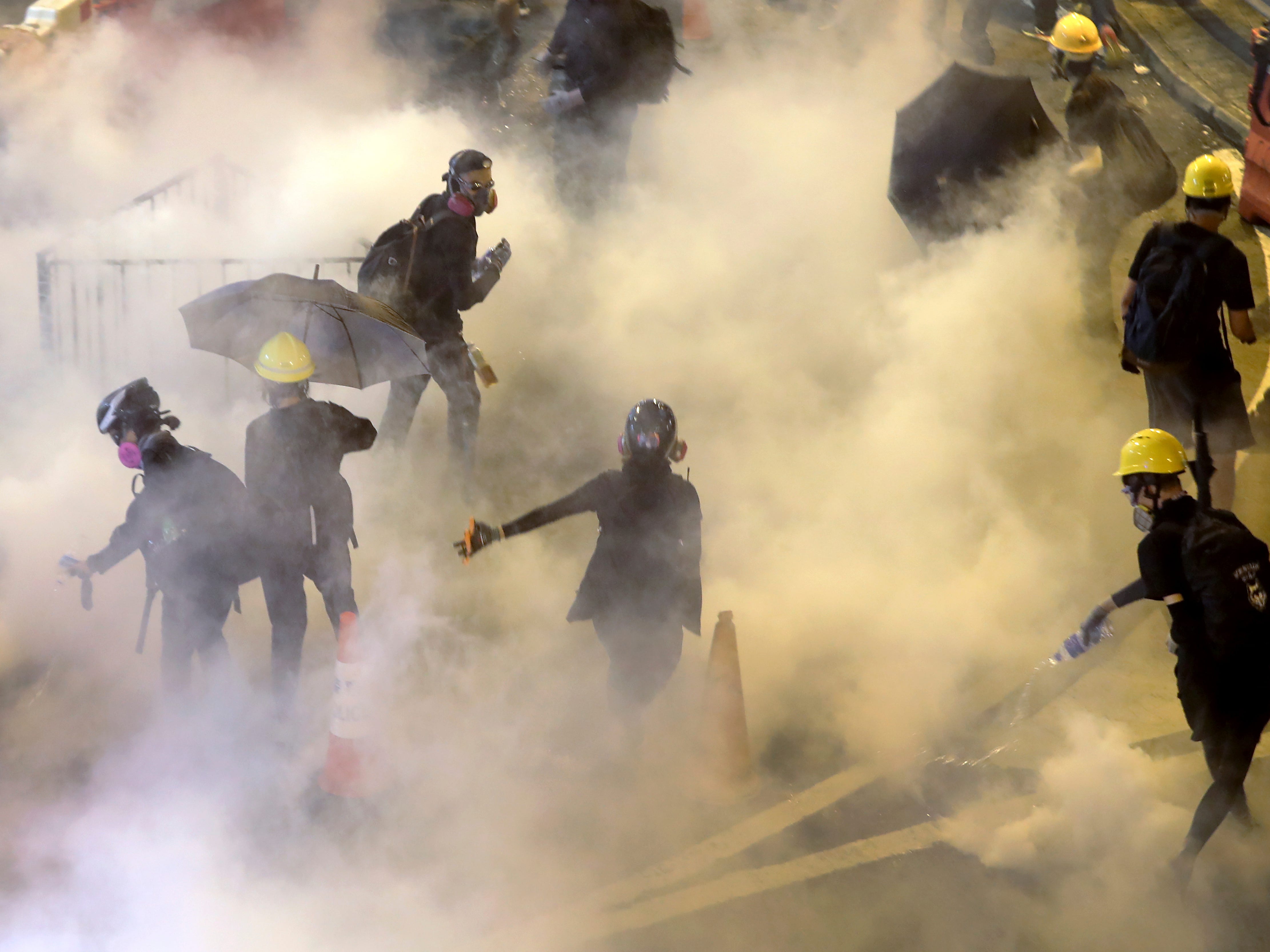 Protesters react to tear gas fired by riot policemen during the anti-extradition bill protest at Causeway Bay in Hong Kong. 