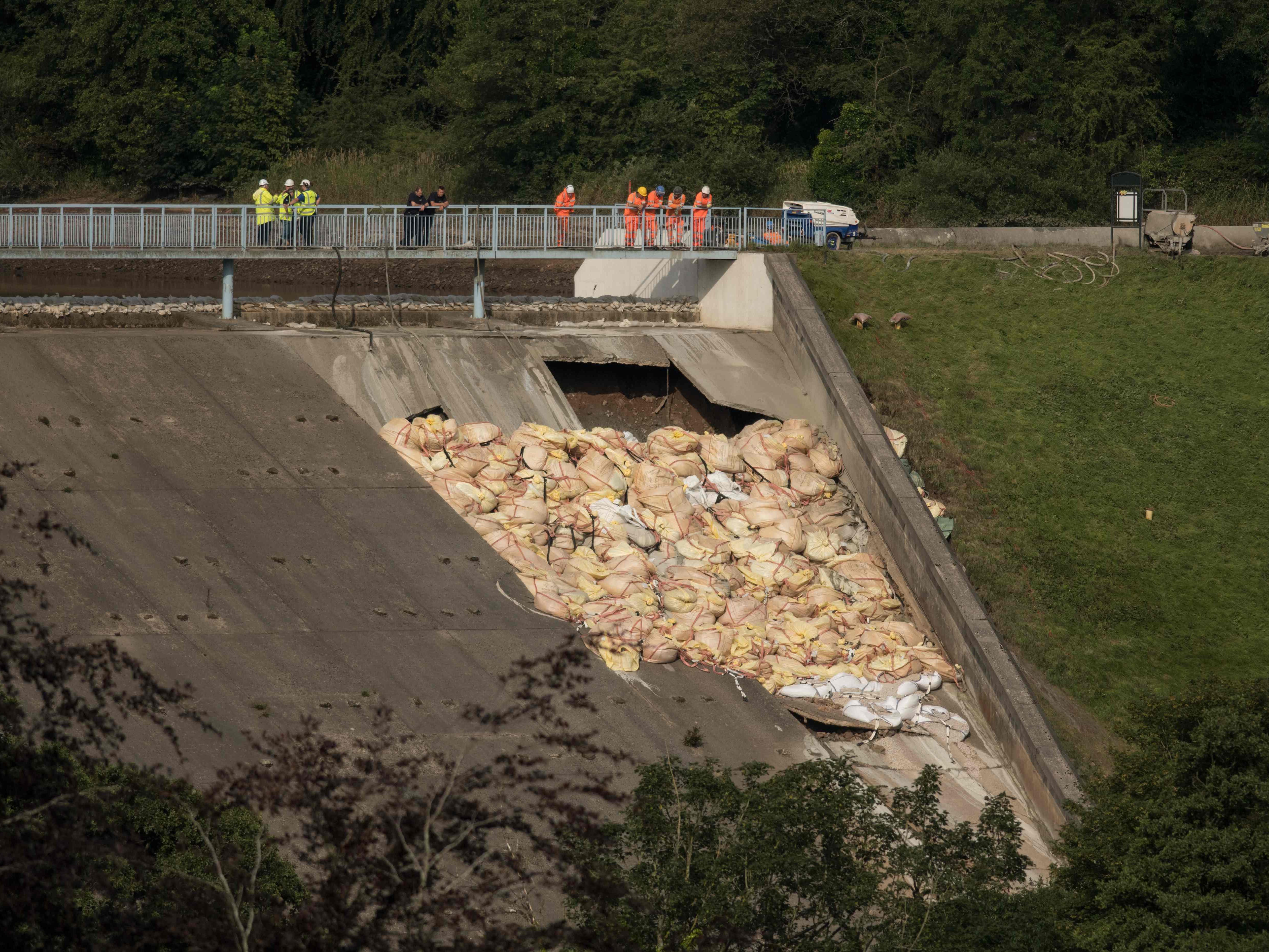 Engineers and members of emergency services assess the damaged spillway of the Toddbrook Reservoir dam, above the town of Whaley Bridge in northern England.