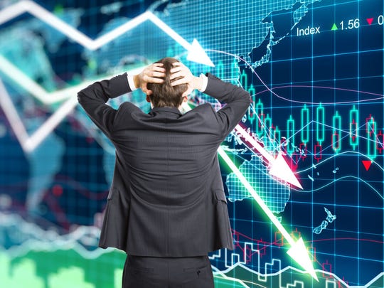 Man holding head in front of stock charts.