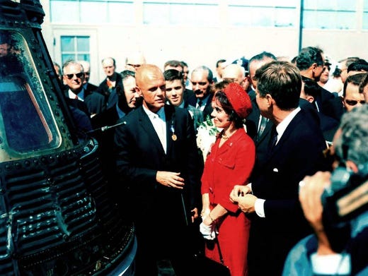 John Glenn, stands next to his Friendship 7 capsule in which he made his historic orbital flight, meets with President John F. Kennedy. Mrs. Glenn stands next to her husband. Earlier that day, President Kennedy presented the NASA Distinguished Service Award to Glenn.