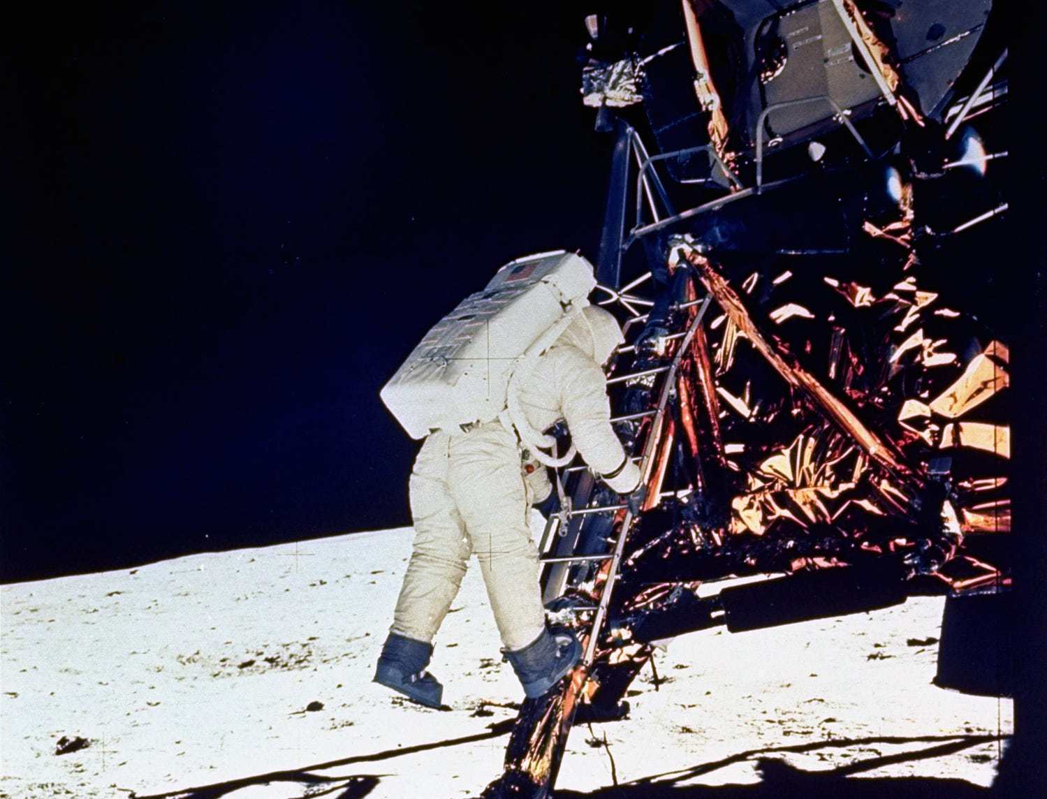 Astronaut Edwin E. Aldrin, Jr., lunar module pilot, descends steps of Lunar Module ladder as he prepares to walk on the moon, July 20, 1969. He had just egressed the LM. This picture was taken by Astronaut Neil A. Armstrong, Commander, with a 70mm 1 surface camera during the Apollo 11 extravehicular activity.