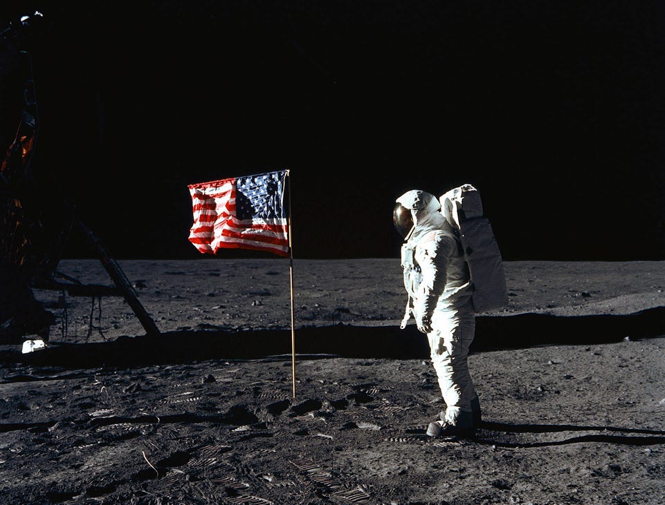 Astronaut Edwin E. Aldrin, Jr., lunar module pilot of the first lunar landing mission, poses for a photograph beside the deployed US flag during Apollo 11 Extravehicular Activity (EVA) on the lunar surface area called the Sea of Tranquility. The Lunar Module (LM) is on the left, and the footprints of the astronauts are clearly visible in the soil of the Moon. Astronaut Neil A. Armstrong, commander, took this picture with a 70mm Hasselblad lunar surface camera on July 20, 1969.