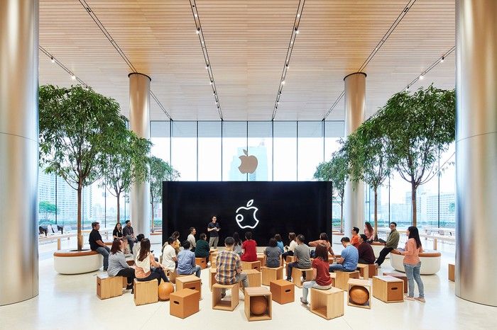 Apple Store with two dozen people watching a presentation.