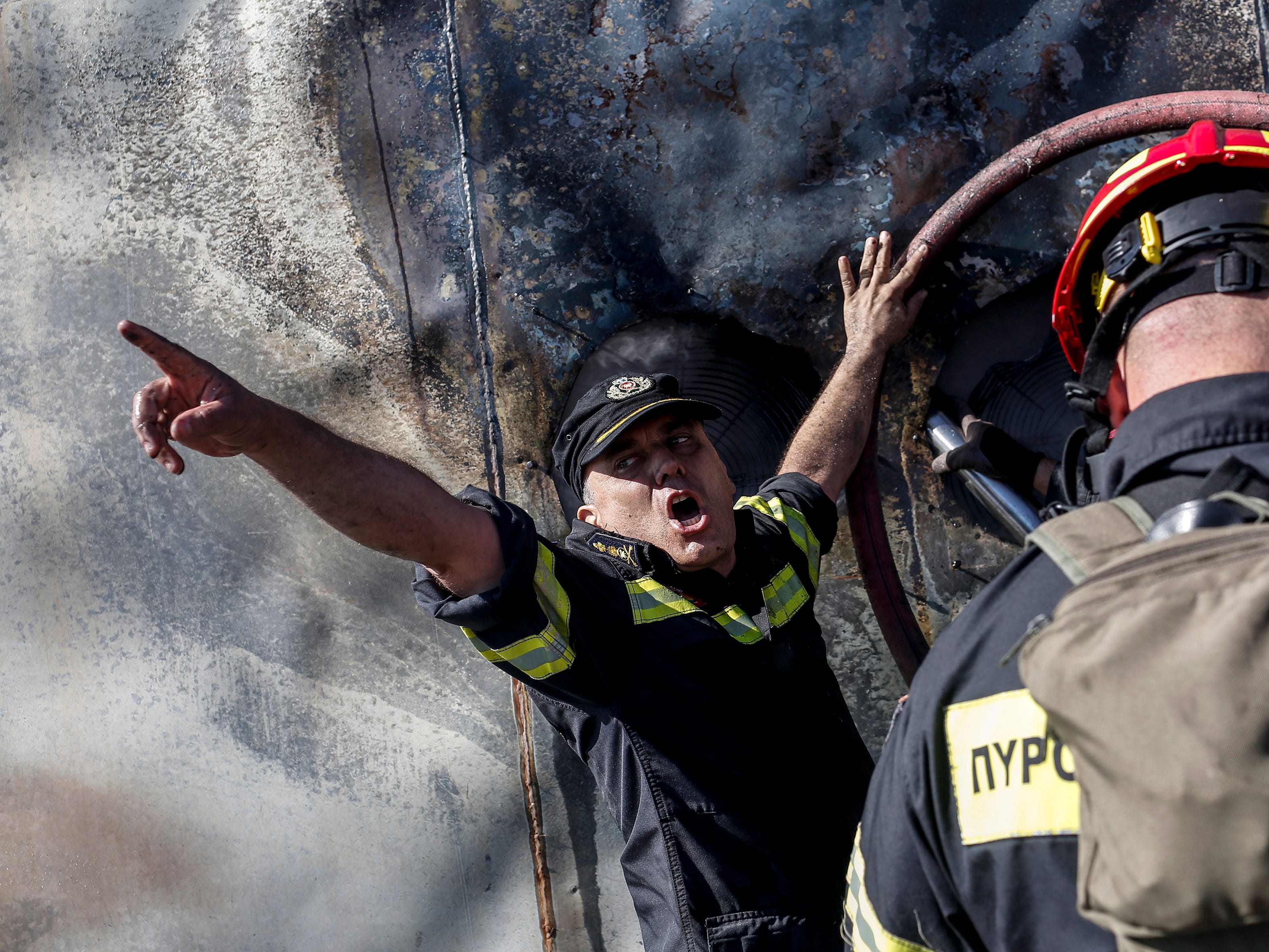 Firefighters try to extinguish a wildfire burning container boxes with telecommunication and radio equipment at the Radion Antenna Park atop of Ymmitos Mountain, after a wildfire that broke out at the foot of the mountain on the outskirt of Athens, Greece.