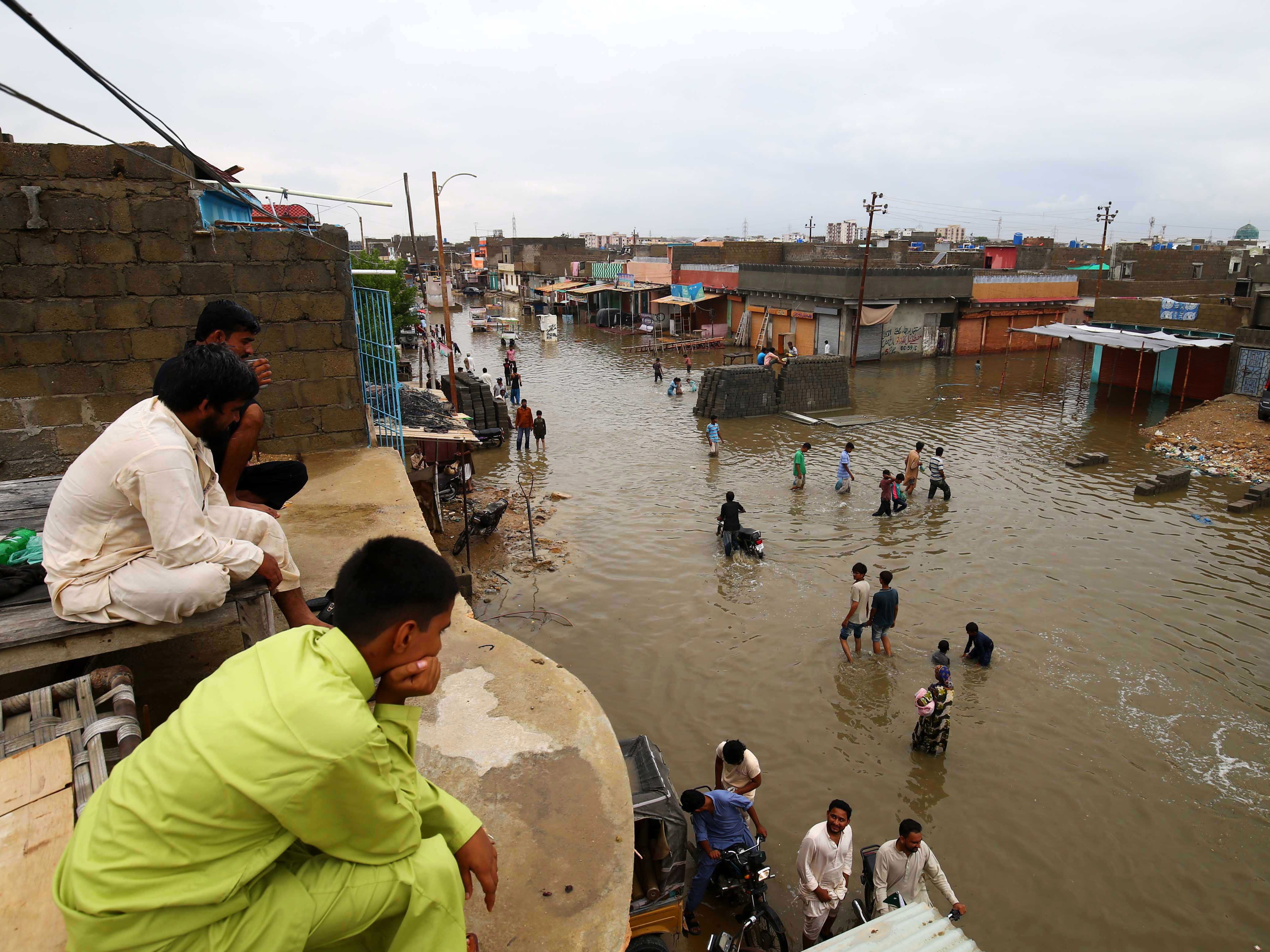 People make their way through a flooded road from heavy monsoon rains in Karachi, Pakistan. At least twelve people lost their lives due to electrocution as heavy rain lashed the region.