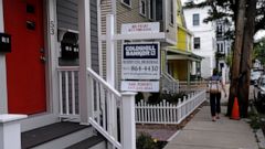 In this Tuesday, Aug. 13, 2019, photo a woman walks past a home listed in Cambridge, Mass. On Thursday, Aug. 15, Freddie Mac reports on this week’s average U.S. mortgage rates. (AP Photo/Charles Krupa)