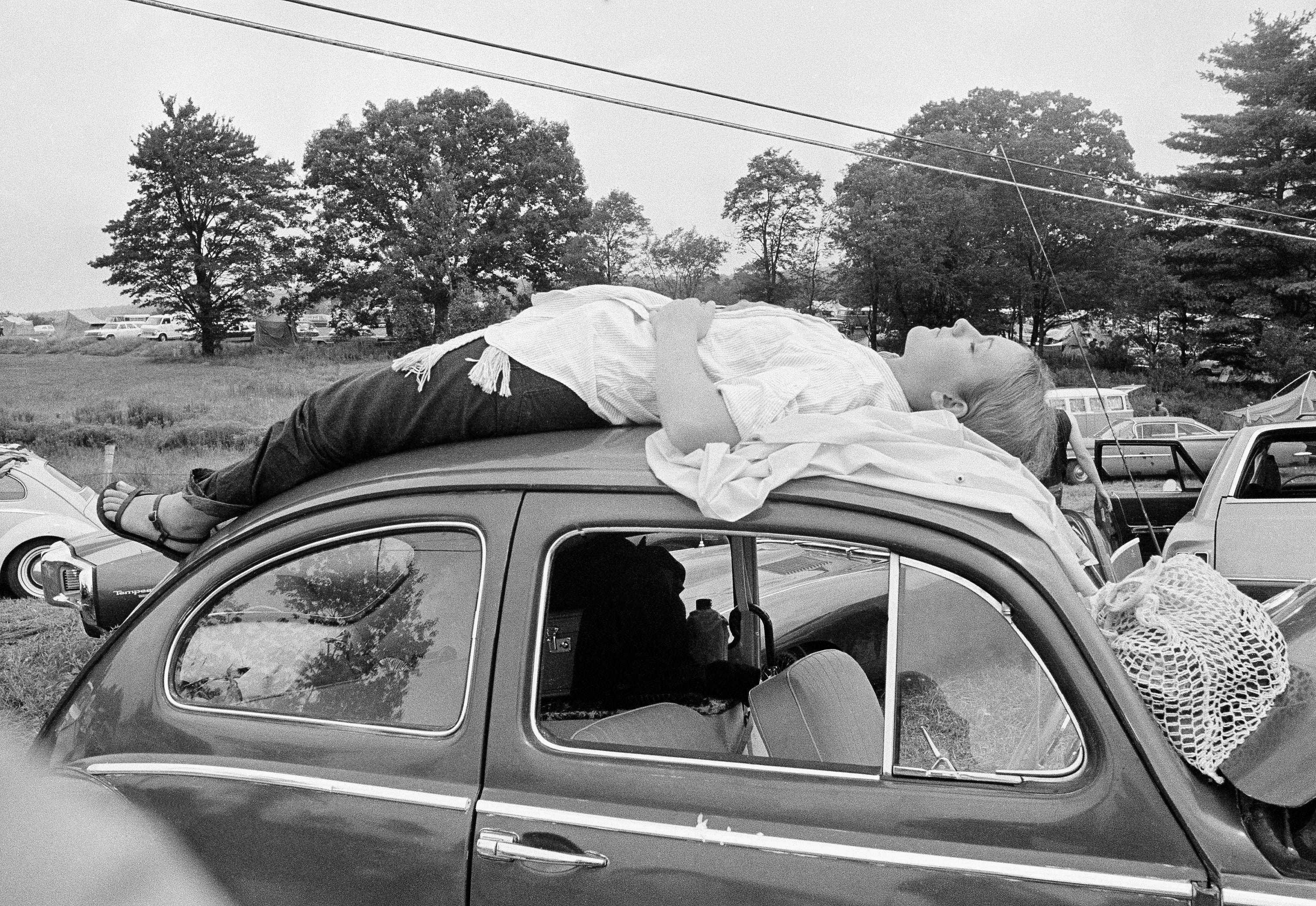 A girl naps on top of her car, while trying to reach the music festival at Woodstock, N.Y., Aug. 16, 1969.