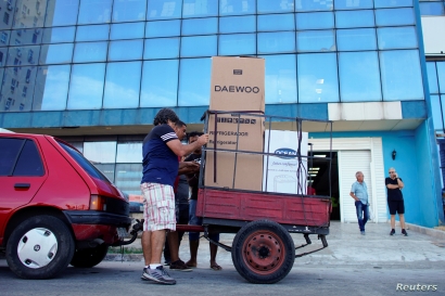 People put into a car trailer a refrigerator and a washing machine just bought from a shop selling products for dollars in…