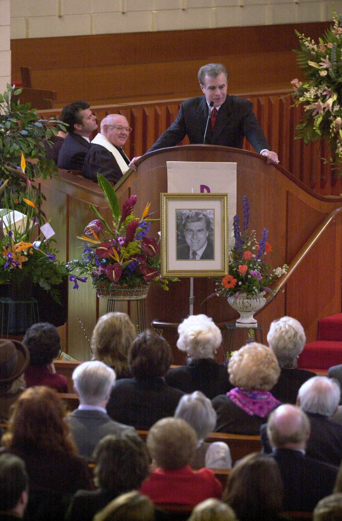 Text: 2001.0118.06.01 Rob Braun delivers a portion of a eulogy written by his brother Doug (background far left) as Rev. Gene Wells look on. Braun's sister Melissa Braun also delivered part of the eulogy as well. A photograph of Bob Braun was displayed at the front of the church during the service. Funeral services for Bob Braun were held at the First United Methodist Church in Madeira. Photographed Thursday Jan.18, 2001.