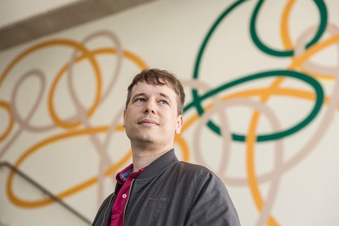 Colour photo of artist Ryan Presley looking off camera and standing at the entrance of the Museum of Contemporary Art in Sydney.