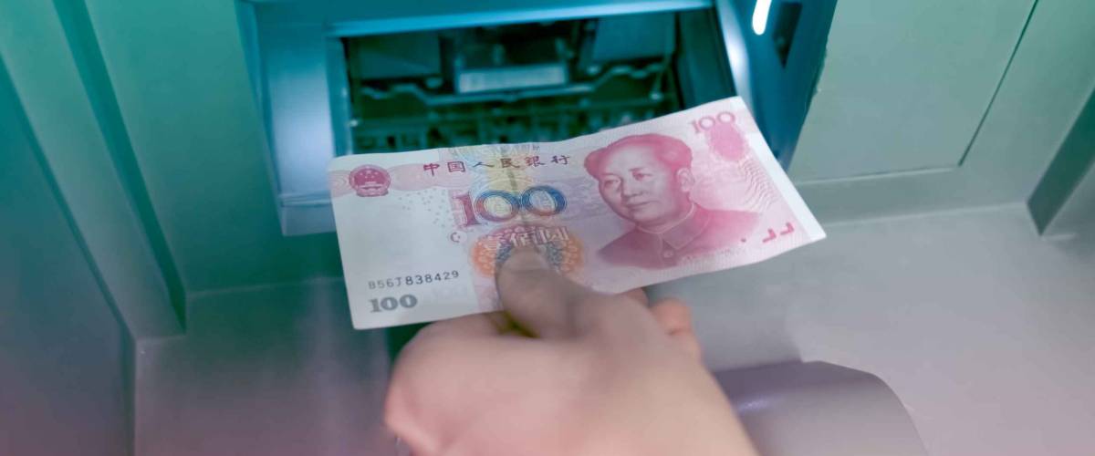 Hand with Chinese RMB placed money in ATM keep it in a saving bank account.