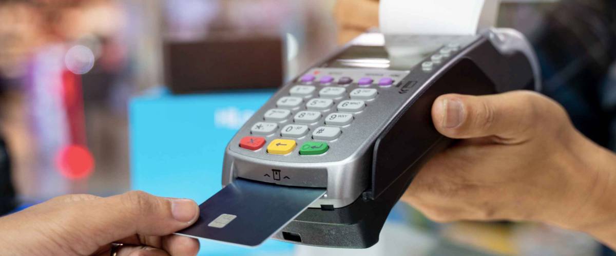 Cropped view of womens hand using credit card to make contactless payment on chip and pin machine