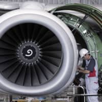 A Japan Airlines Co. engineer works on a Boeing 737 in a hangar at Haneda Airport in Tokyo.