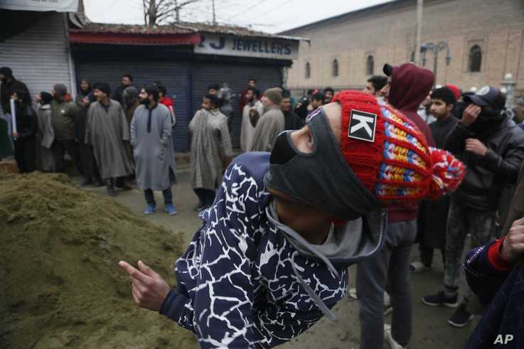 A masked Kashmiri boy throws stones at a police drone flying over Jamia Masjid mosque where Kashmiris are offering their first…