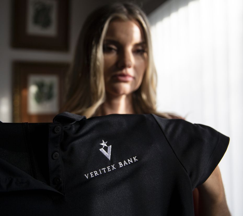 Jamie Nickerson holds a shirt she wore as a teller at Veritex Community Bank on Merrick Street on Nov. 25, 2019 in Fort Worth home. A July 2018 botched robbery at the bank left her and two other employees injured. Nickerson said she will never be a teller again. (Juan Figueroa/ The Dallas Morning News)