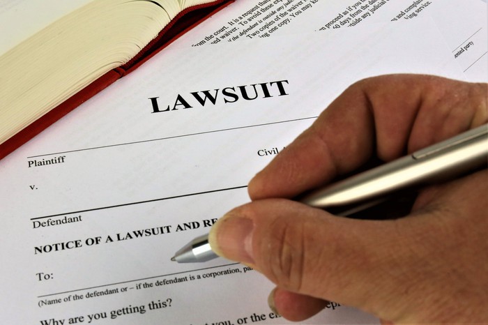 A person filling out legal lawsuit documents. 