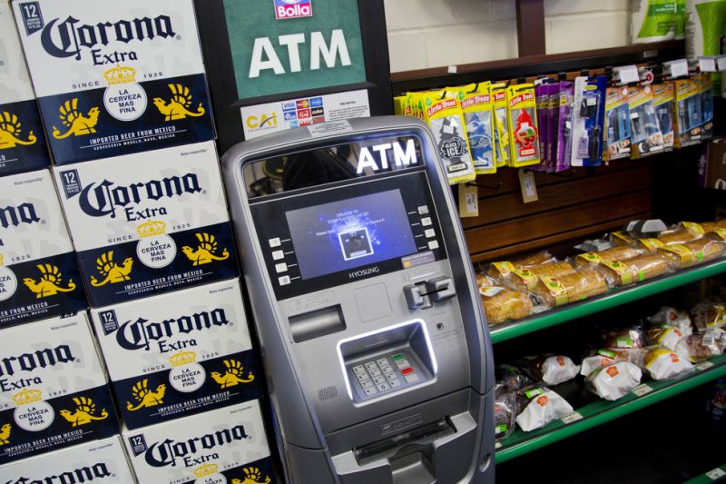 FILE - In this April 18, 2018, file photo, an ATM machine is in use at a New York convenience store. If you find yourself short on cash while on vacation, it might seem easiest to hit up the nearest ATM. But if that handy machine is not in your bank’s network, you could get a double whammy of fees: The ATM owner will probably charge a few dollars for the convenience, and your own bank may tack on an extra $2.50 or so. (AP Photo/Mark Lennihan, File)