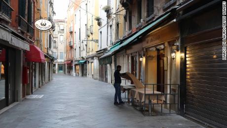 A waiter sets a table in a restaurant on an empty street in Venice, Italy. 