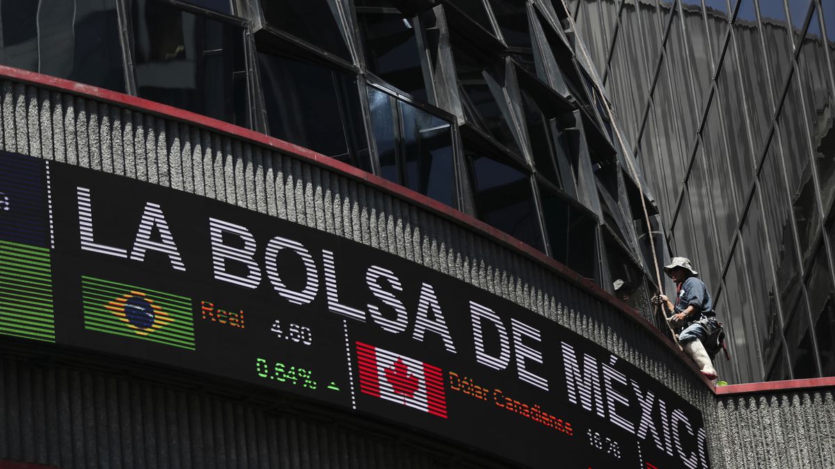 A man cleans the windows of Mexico's Exchange building in Mexico City, Tuesday, March 17, 2020. The coronavirus outbreak and dropping oil prices have resulted in plunging Latin American markets and currencies. (AP Photo/Fernando Llano)