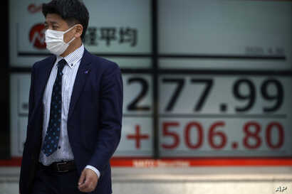 A man walks past an electronic stock board showing Japan's Nikkei 225 index at a securities firm in Tokyo Thursday, April 30,…