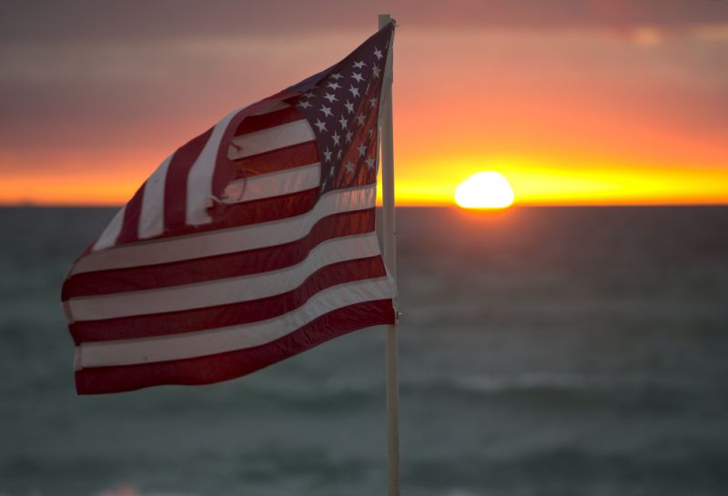 An American flag flutters in the breeze as the sun rises on Hollywood Beach, Tuesday, Feb. 2, 2016, in Hollywood, Fla. (AP Photo/Wilfredo Lee)