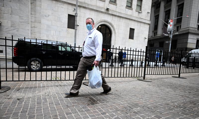 A Trader wearing a mask arrives with his special keyboard before the opening bell at the New York Stock Exchange (NYSE) on May 26, 2020 on Wall Street in New York City. - Global stock markets climbed Monday, buoyed by the prospect of further easing of coronavirus lockdowns despite sharp increases in case rates in some countries such as Brazil. Over the weekend, US President Donald Trump imposed travel limits on Brazil, now the second worst affected country after the United States, reminding markets that while the coronavirus outlook is better, the crisis is far from over. (Photo by Johannes EISELE / AFP) (Photo by JOHANNES EISELE/AFP via Getty Images)