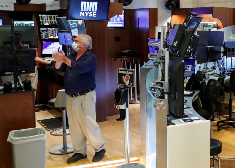 A trader wearing a mask reacts at the closing bell, on the first day of in person trading since the closure during the outbreak of the coronavirus disease (COVID-19) on the floor at the New York Stock Exchange (NYSE) in New York, U.S., May 26, 2020. REUTERS/Brendan McDermid