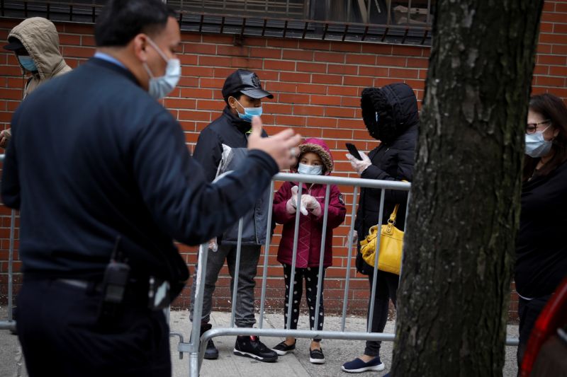 An official wearing a protective face mask speaks to people waiting in line outside NYC Health + Hospitals/Gotham Health Morrisania neighborhood health center, one of New York City's new walk-in COVID-19 testing centers, during the outbreak of the coronavirus disease (COVID-19) in the Bronx borough of New York City, New York, U.S., April 20, 2020. REUTERS/Mike Segar