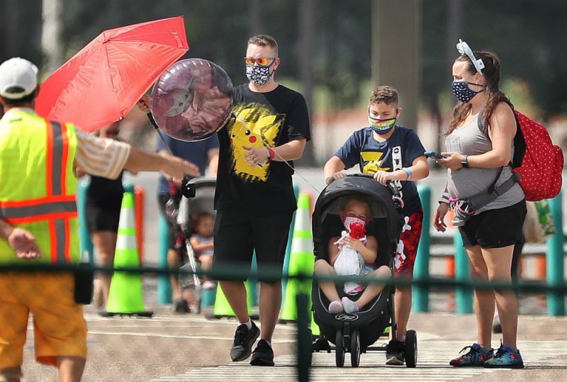 Guests wearing masks walk to the entrance of Walt Disney World's Magic Kingdom in Orlando, Florida, on Saturday, July 11, 2020. The theme park reopened at limited capacity during the Coronavirus pandemic. (Stephen M. Dowell/Orlando Sentinel/Tribune News Service via Getty Images)