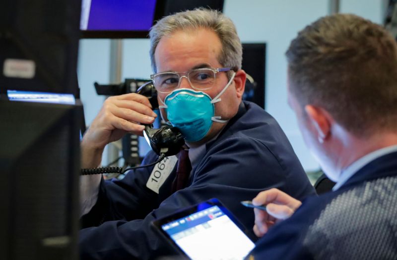 A trader wears a face mask on the floor of the New York Stock Exchange (NYSE) following traders testing positive for Coronavirus disease (COVID-19), in New York, U.S., March 19, 2020. REUTERS/Lucas Jackson