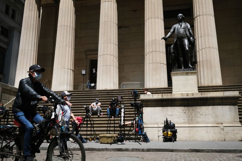 NEW YORK, NEW YORK - MAY 26: Television journalists and others gather across from the entrance to the New York Stock Exchange (NYSE) on the first day that traders are allowed back onto the historic floor of the exchange on May 26, 2020 in New York City. While only a small number of traders will be returning at this time, those that do will have to take temperature checks and wear face masks at all times while on the floor. The Dow rose over 600 points in morning trading as investors see economic activity in America picking up. (Photo by Spencer Platt/Getty Images)