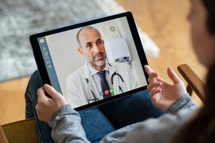 A patient using a tablet to have a virtual consultation with a physician. 