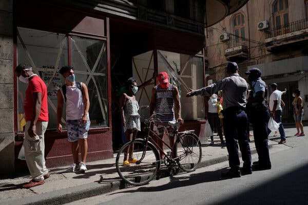 Police officers in Havana organizing a line of people waiting to buy food. Lines are often many hours long.