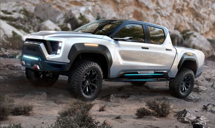 A silver Nikola Badger pickup in front of a rocky background